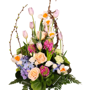 En färgglad blomsterarrangemang med rosor, tulpaner, påskliljor och hortensior, arrangerade med böjda grenar och gröna blad.